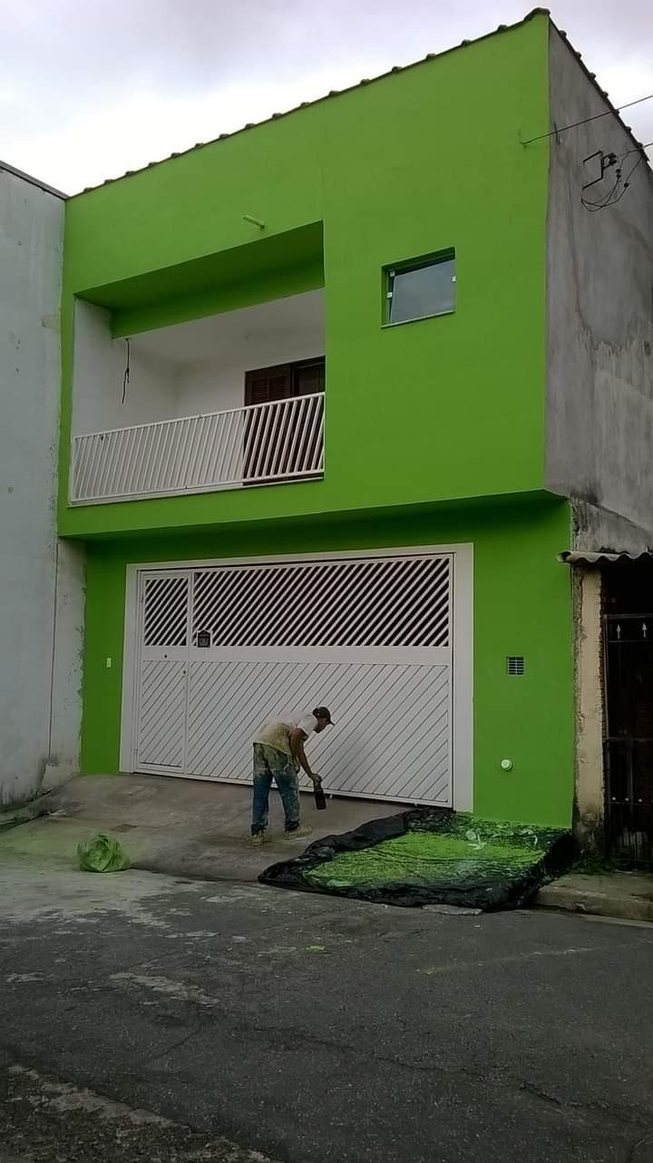 Pintor da Prime Pintura aplicando tinta em portão de fachada residencial verde