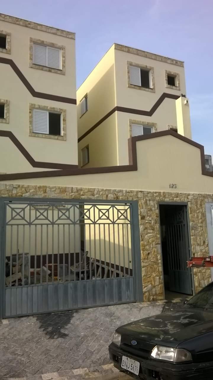 Fachada residencial em tom bege com detalhes em pedra e portão de ferro pintados pela Prime Pintura