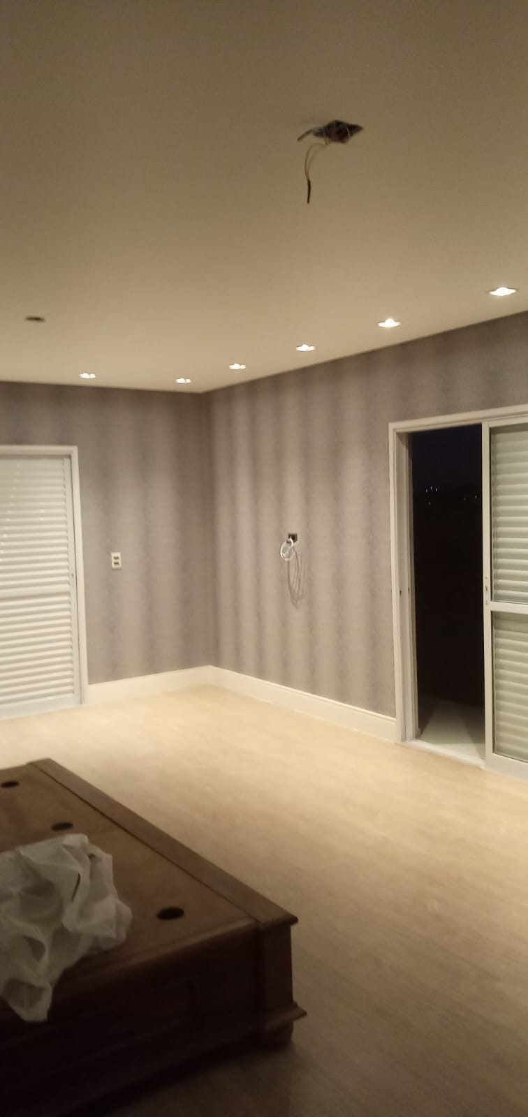 Quarto com parede em revestimento cinza e iluminação embutida no teto, obra da Prime Pintura